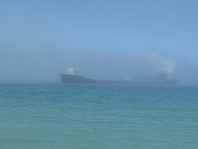 I heard her repeated fog horn soundings long before she materialized.
