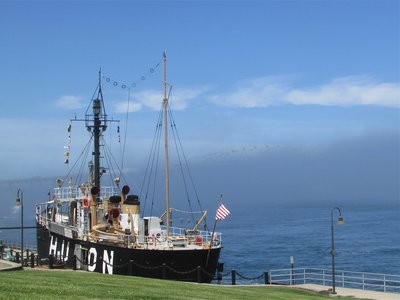 Huron Lightship with only a small portion of the Bluewater Bridges (above and slightly to the right of the American flag) visible in the fog.
