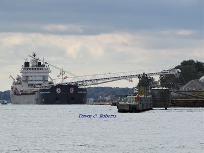 Algoma Compass at Bluewater Aggregates (Marysville) with boom extended and her work boat in the water at the back left corner.