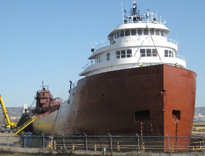 With the newly painted bow exposed, the tarp was moved to the stern where sandblasting and painting took place there as well .