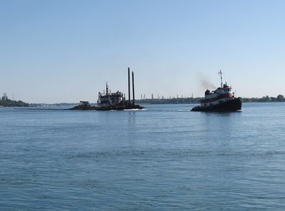 Look closely and you can see a well-marked, long "tail" of pipe behind the last barge.  With my zoom off, the entire consist was too long to photograph any closer.